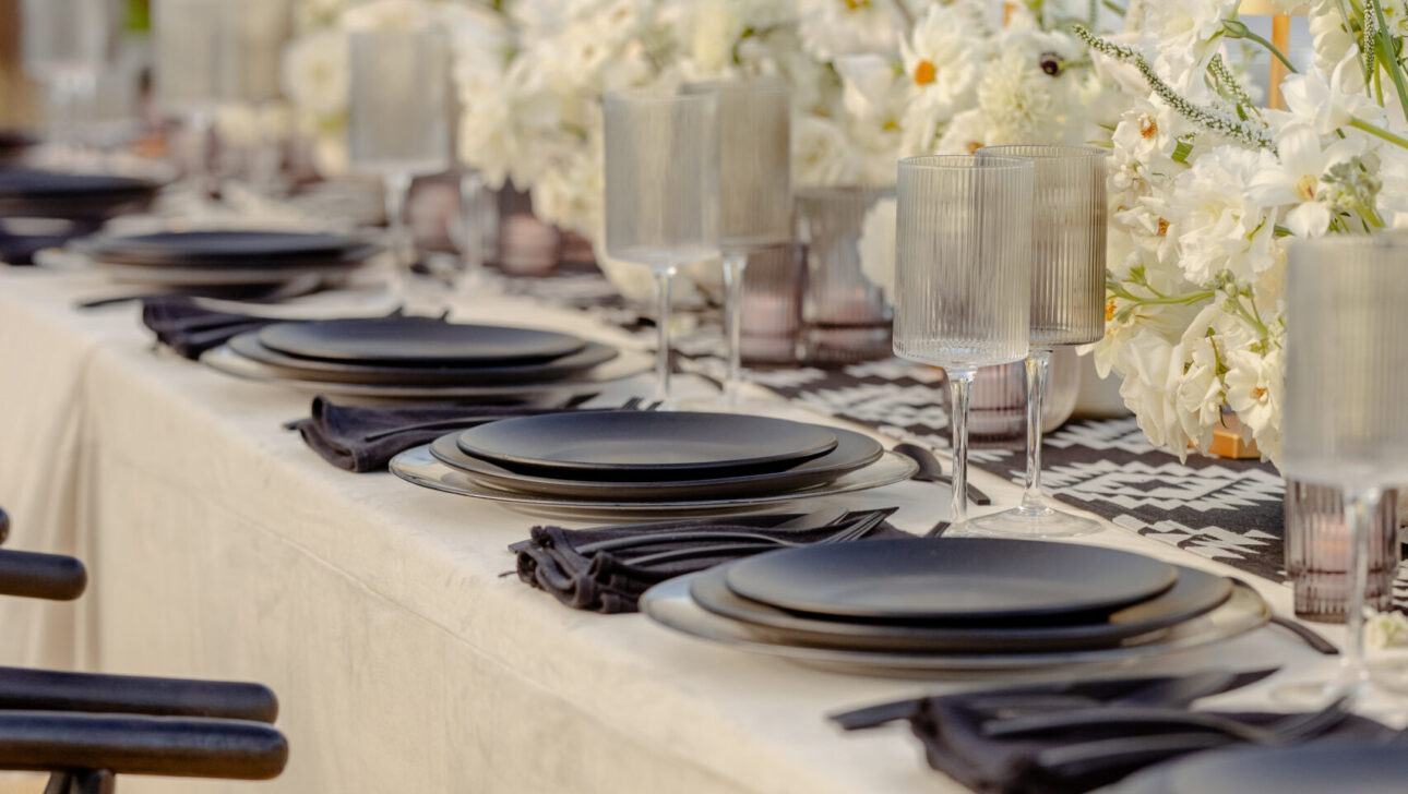 Table setting with black chargers, black chairs and crisp white linens and florals.
