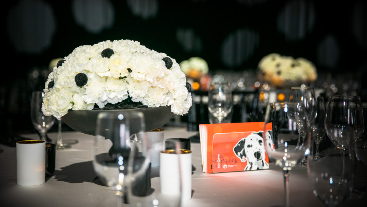 Elegant table setting with white floral centerpiece and spot-themed decor, designed by a top event planning company.