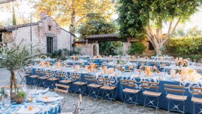 Outdoor courtyard dinner setting under a canopy of trees and twinkling lights.