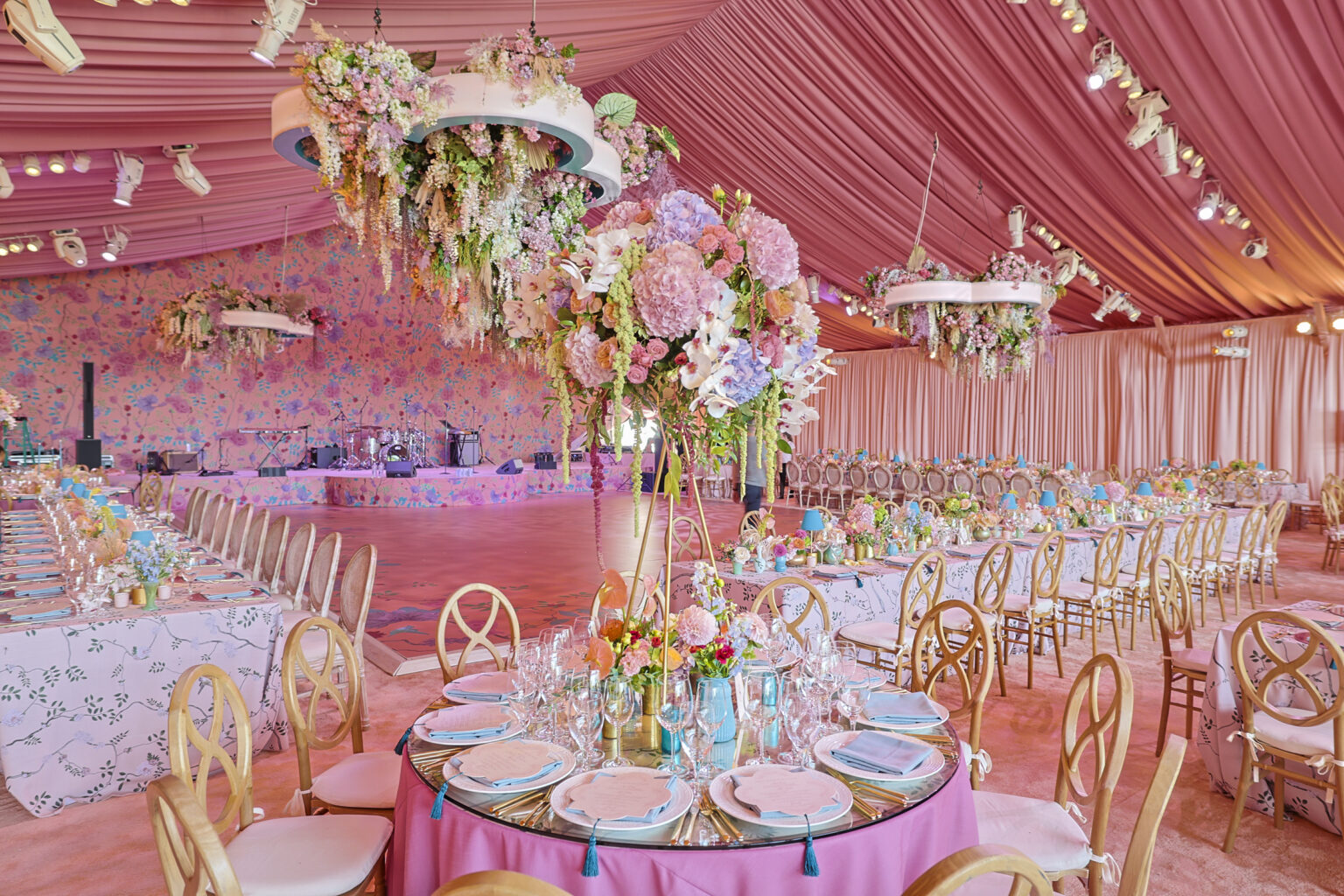Extravagant wedding reception with draped pink tent ceilings and custom cascading floral chandelier. Designed by JWennes Events.
